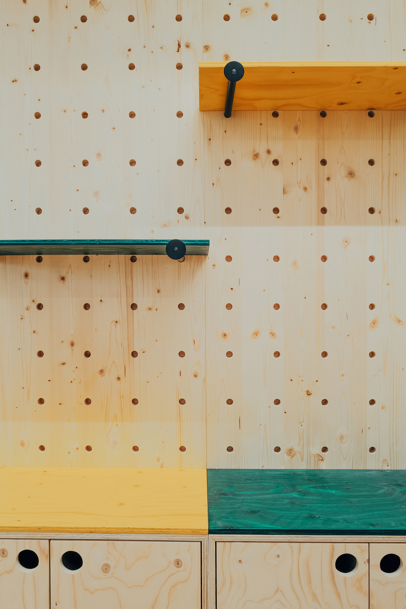 Detail des modularen Möbelsystems QuuBox mit Lochwand, farbigen Ablageflächen und Holzelementen