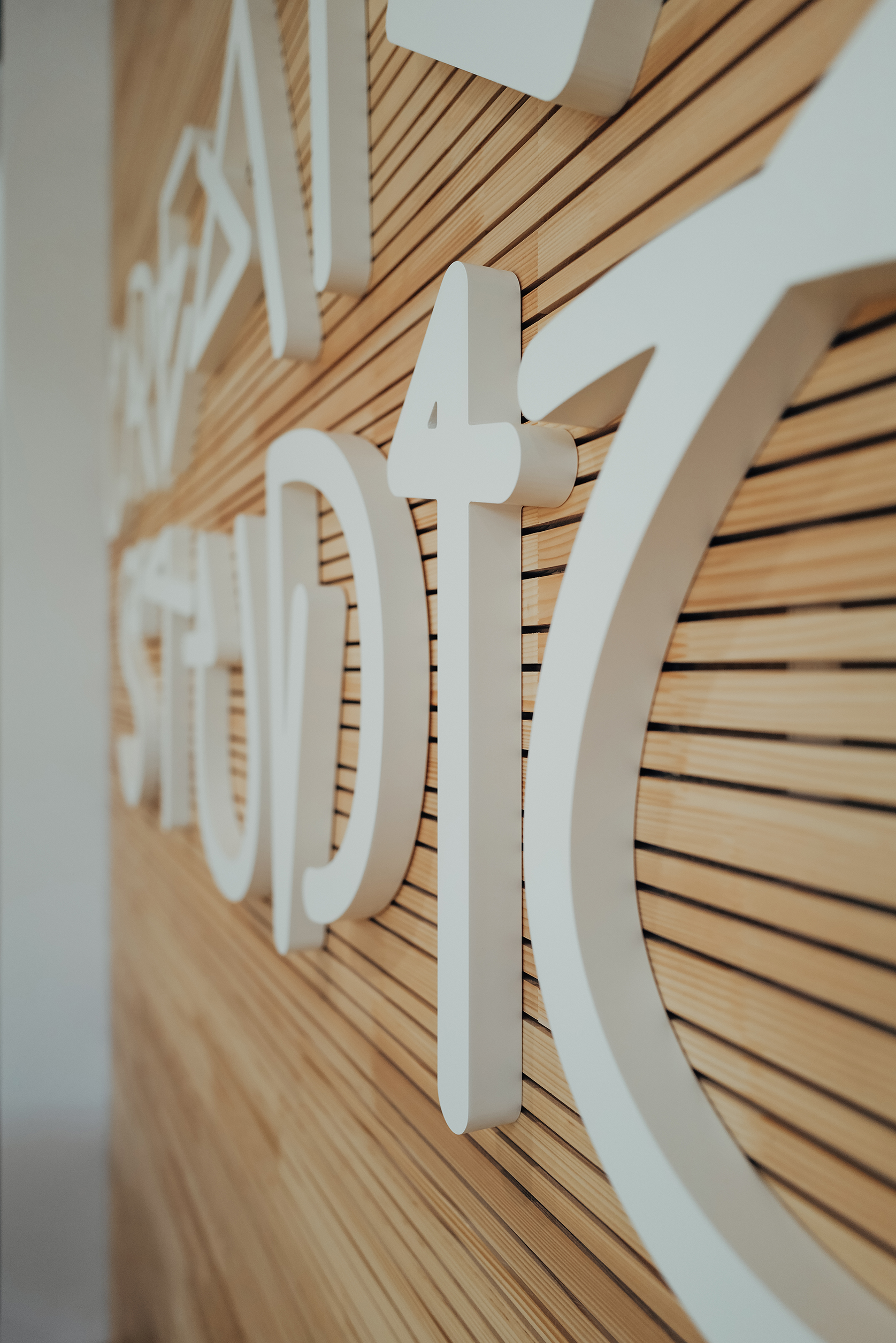 Detailaufnahme der individuellen Creator-Studio-Typografie auf einer Holzlamellenwand