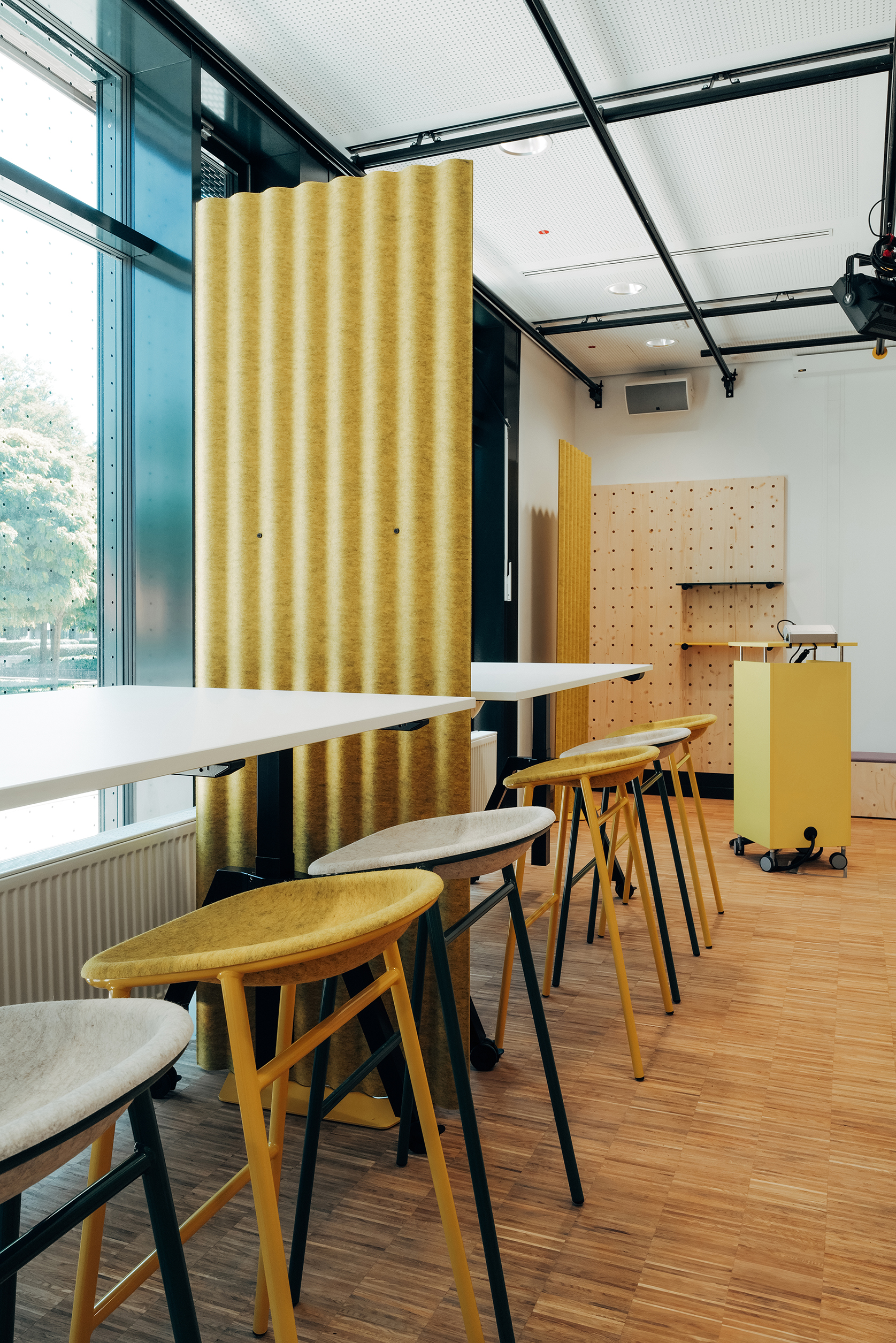 Flexibler Arbeitsbereich im THIS mit Hochtischen, Sitzmöbeln und mobilen gelben Raumelementen
