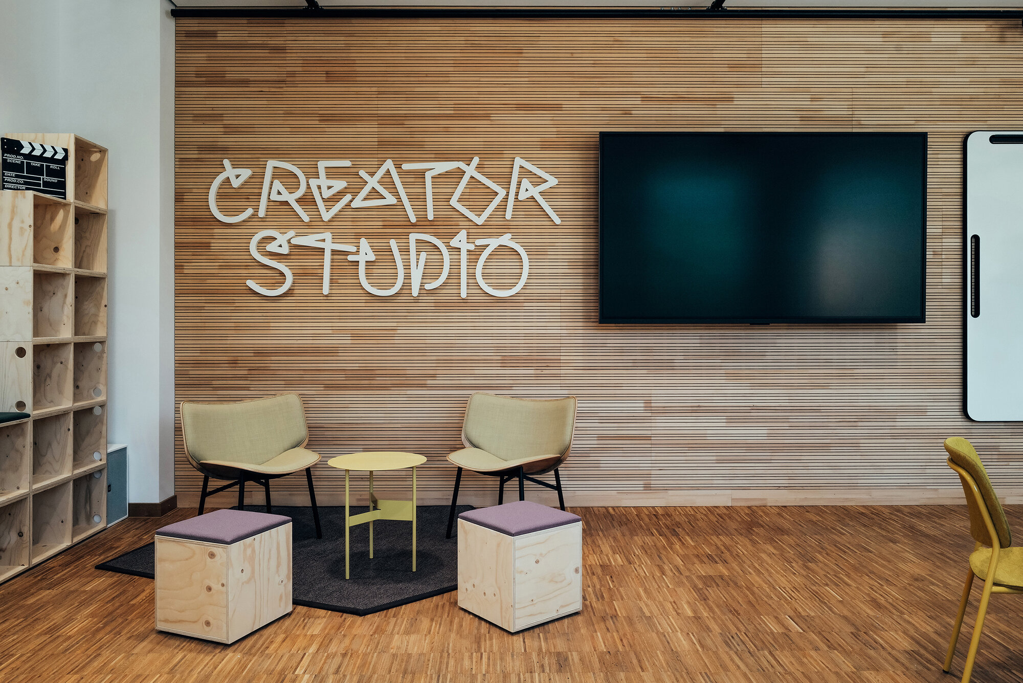 Lounge- und Arbeitsbereich im Creator Studio mit modularen Holzmöbeln und farbigen Sitzmöbeln