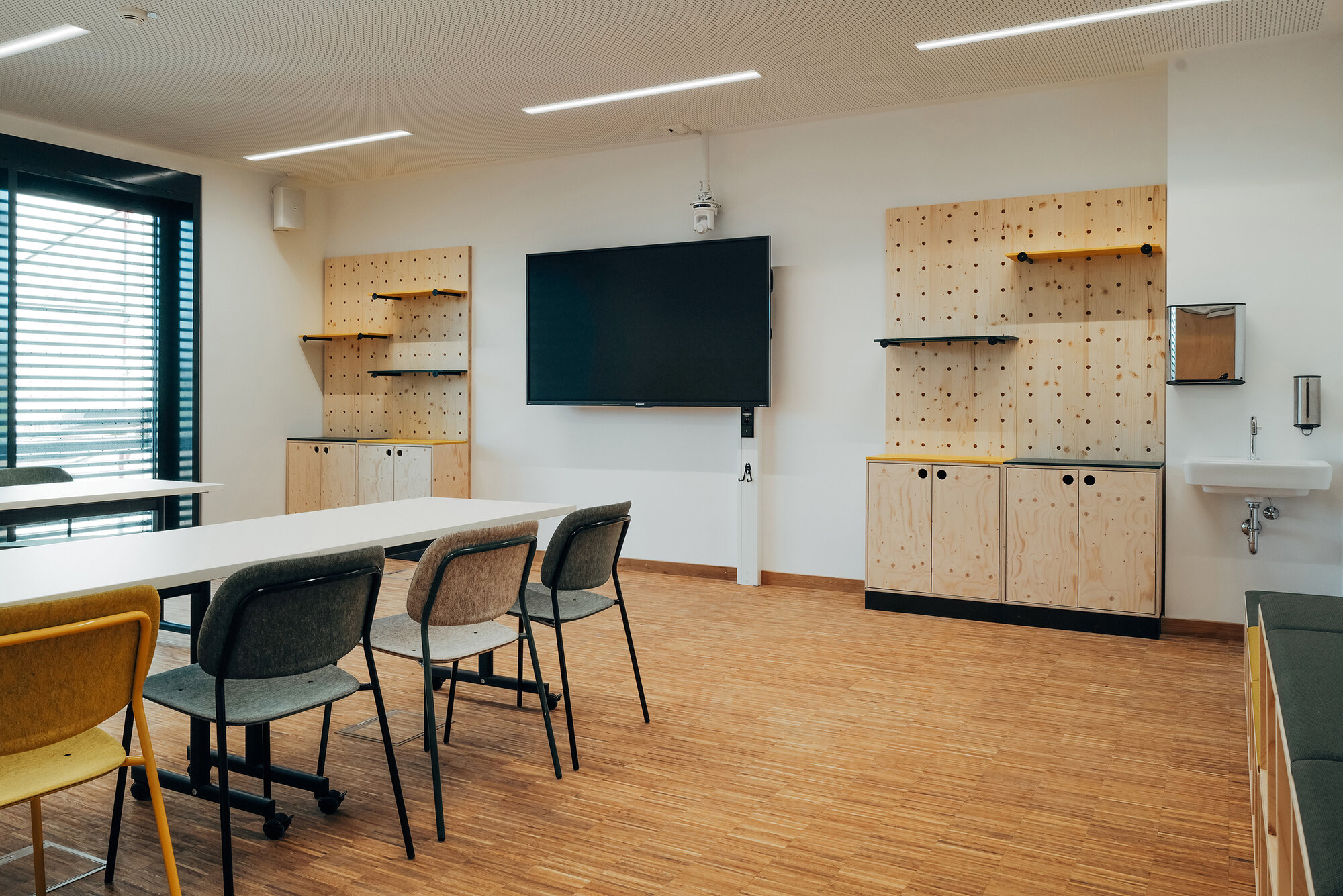Flexibler Seminarraum mit mobilen Tischen, farbigen Sitzmöbeln und QuuBox modularen Holzelementen